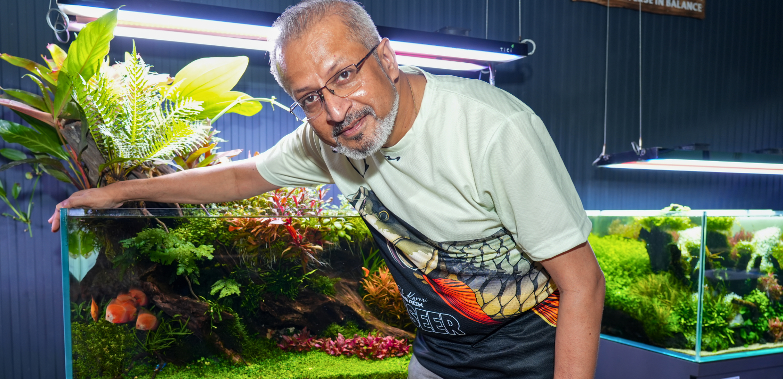 Man interacting with the ‘Island of Life’ planted aquarium at TiCi NatureLab, featuring both terrestrial plants and lush aquatic plants, bog wood hardscape and a thriving freshwater ecosystem.