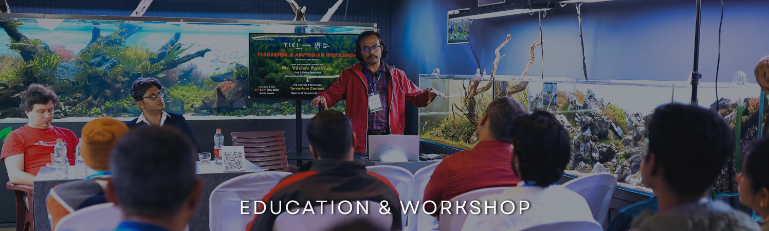 Expert speaker conducting a Terrarium and Amphibian Workshop at TiCi NatureLab, presenting to attendees in a gallery surrounded by large aquascaped aquariums and nature-inspired aquatic displays.